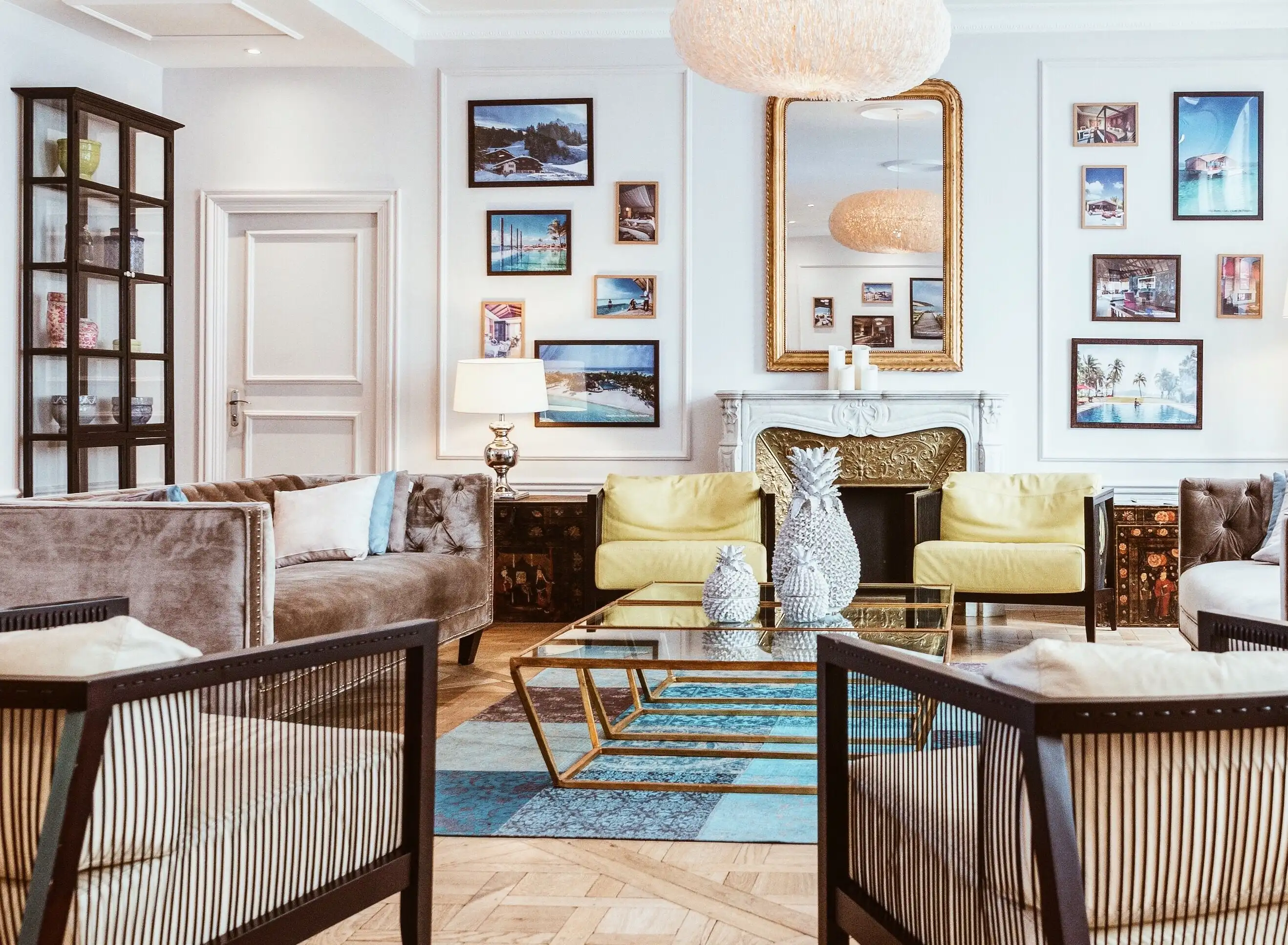 A bright living room with a gilded mirror over the fireplace and a gallery wall
